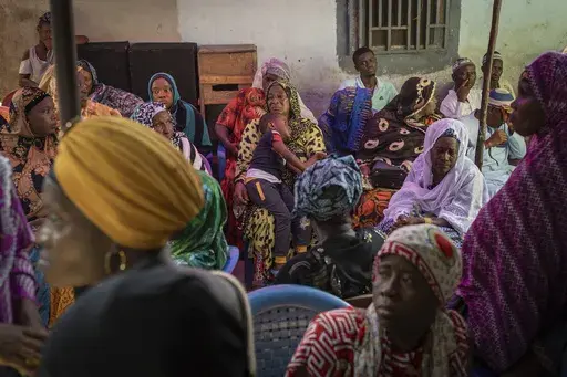Mourners gather at the house of Ousmane Sylla's mother after his burial in Matoto Bonagui, a suburb of Conakry, Guinea, Tuesday, April 9, 2024. In Italy, he found despair. He spent months in a crowded, squalid migrant detention center, unable to contact his family. He died by suicide in February after other detainees said he became depressed and withdrawn. (AP Photo/Misper Apawu)
