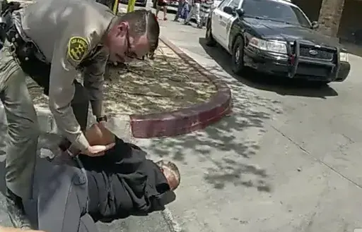 In this image taken from police body camera provided by Los Angeles Sheriff's office on June 24, 2023, a Sheriff's deputies arrested a couple in a grocery store parking lot in Lancaster, Calif. The Los Angeles County sheriff has opened an investigation into two deputies' actions after a bystander's cellphone footage showed one of them tackling a woman while she filmed her husband being handcuffed in what the scandal-ridden department described as disturbing. (Los Angeles County Sheriff's Office 