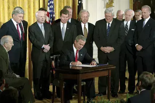 President George W. Bush signs a resolution authorizing the use of force against Iraq, Oct. 16, 2002, in the East Room of the White House. Left to right, Sen. Jesse Helms, R-N.C., Sen. John Warner, R-Va., Sen. John McCain, R-Ariz., Rep. Roy Blunt, R-Mo., Sen. Joseph Lieberman, D-Conn., Speaker the House Dennis Hastert, R-Ill., Rep. Tom Lantos, D-Calif., Sen. Joseph Biden, D-Del. (AP Photo/Ron Edmonds, File)