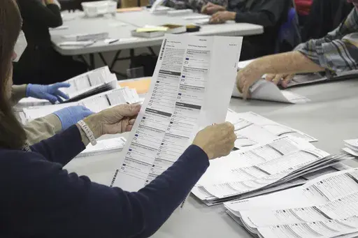 An election worker examines a ballot at the Clackamas County Elections office, May 19, 2022, in Oregon City, Ore. Problems with a ballot-sorting machine are delaying the vote count in a suburban Portland, Oregon county where issues with blurry bar codes on mail-in ballots delayed elections results in a key Congressional primary race for two weeks in 2022. (AP Photo/Gillian Flaccus, File)