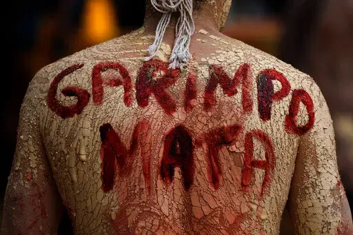 An Indigenous man with a phrase in Portuguese painted on his back that translates to "Mining Kills," participates in a protest against the increase of mining activities that are encroaching on his land, in front of the Ministry of Mines and Energy, in Brasilia, Brazil, Monday, April 11, 2022. A fast-expanding network of antennae is empowering Indigenous groups to use phones, video cameras and social media to galvanize the public and pressure authorities to respond swiftly to threats from gold mi