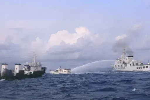In this handout photo provided by the Philippine Coast Guard, a Chinese Coast Guard ship uses water cannons on Philippine navy-operated supply boat M/L Kalayaan as it approaches Second Thomas Shoal, locally known as Ayungin Shoal, in the disputed South China Sea on Sunday Dec. 10, 2023. The Chinese coast guard targeted Philippine vessels with water cannon blasts Sunday and rammed one of them, causing damage and endangering Filipino crew members off a disputed shoal in the South China Sea, just a