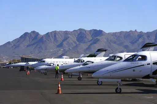 A Scottsdale Airport staffer waits on a private jet, as the airport gears up for the expected dramactic increase in private jet traffic, leading up to the NFL Super Bowl LVII football game at Scottsdale Airport in Scottsdale, Ariz., Thursday, Feb. 2, 2023. (AP Photo/Ross D. Franklin)