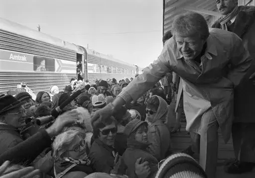 President-elect Jimmy Carter leans over to shake hands with some of the people riding the "Peanut Special" to Washington, Jan. 19, 1977. They will travel all night, arriving in Washington in time for Carter's inauguration as president on Jan. 20. (AP Photo, File)