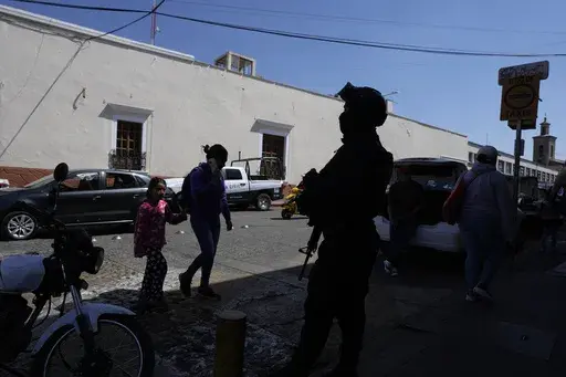 A municipal police officer stands guard in Maravatio, Michoacan state, Mexico, Tuesday, Feb. 27, 2024. Two mayoral hopefuls in this city were gunned down the previous day within hours of each other, ahead of the June 2 national elections. (AP Photo/Fernando Llano)