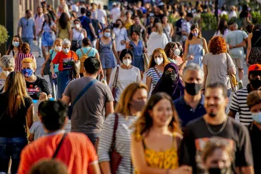 People wearing a face mask to protect against the spread of coronavirus walk along a street in downtown Barcelona, Spain, July 3, 2021. Some European countries such as Spain are making tentative plans for when they might start treating COVID-19 as an "endemic" disease, but the World Health Organization and other officials have warned that the world is nowhere close to declaring the pandemic over. (AP Photo/Joan Mateu, File)
