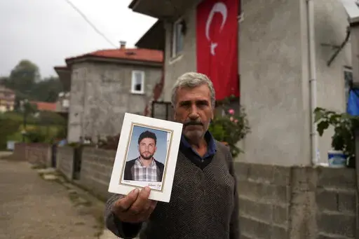 Recep Ayvaz, 62, shows a picture of his son, Selcuk Ayvaz, 33, one of the miners killed in a coal mine explosion, in front of his house in Amasra, in the Black Sea coastal province of Bartin, Turkey, Sunday, Oct. 16, 2022. (AP Photo/Khalil Hamra)