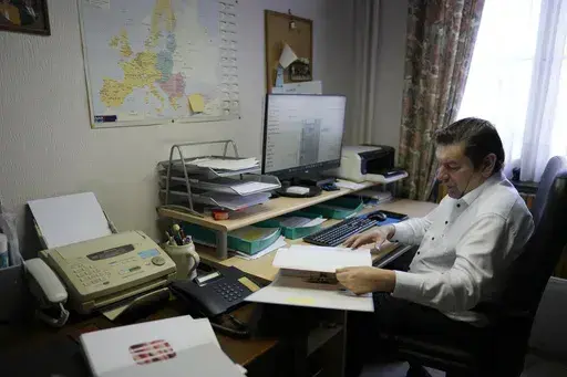 Bart Dochy looks through accounting books and logs entries on his computer at his family farm in Ledegem, Belgium, Tuesday, Feb. 13, 2024. Fickle regulations are a key complaint heard from European farmers protesting over the past weeks, setting up a key theme for the upcoming June 6-9 parliamentary elections in the 27-nation European Union. (AP Photo/Virginia Mayo)