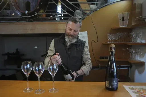 French wine grower David Levasseur opens a bottle of champagne in his wine making facility in Cuchery, eastern France, Monday, March 17, 2025. (AP Photo/Thibault Camus)