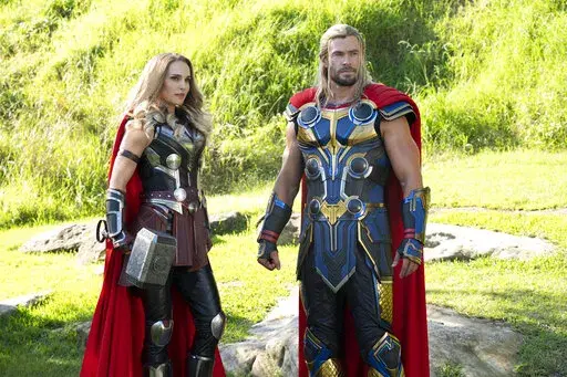 This image released by Marvel Studios shows Natalie Portman, left, and Chris Hemsworth in a scene from "Thor: Love and Thunder." (Jasin Boland/Marvel Studios-Disney via AP)