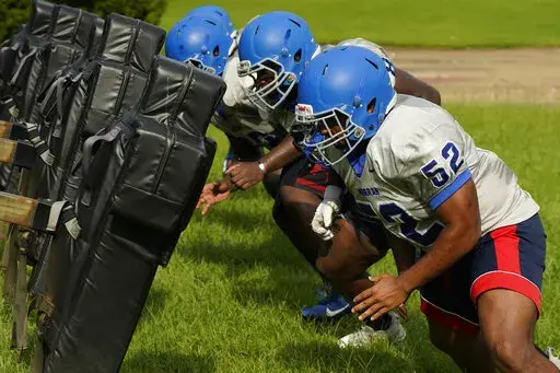 Murrah High School football offensive linemen square up against the blocking sled at practice, Wednesday, Aug. 31, 2022, in Jackson, Miss. The city's low water pressure concerns football coach Marcus Gibson, as it limits his options for washing practice uniforms, towels and other gear his players wear. The recent flood worsened Jackson's longstanding water system problems. (AP Photo/Rogelio V. Solis)