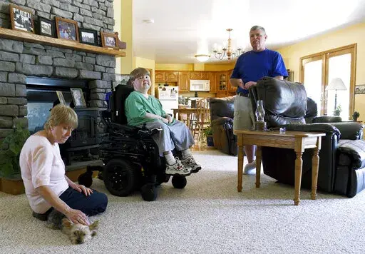 This undated photo shows Terry Horgan with his parents in the family's Montour Falls, N.Y., home. Horgan, a 27-year-old who had Duchenne muscular dystrophy, died last month, Oct. 2022,  according to Cure Rare Disease, a Connecticut-based nonprofit founded by his brother, Rich, to try and save him. Although it’s still unclear what killed him, his death is raising questions about the experiment and the overall prospect of what one ethicist calls designer genetic therapies. (Kate Collins/The Jour
