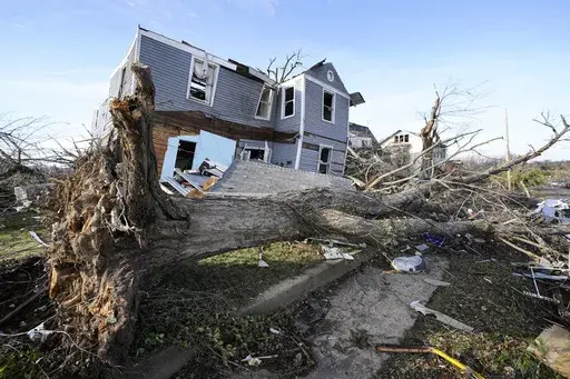 An overturned tree sits in front of a tornado damaged home in Mayfield, Ky., on Dec. 11, 2021. On Friday, March 17, 2023, The Associated Press reported on stories circulating online incorrectly claiming climate, weather or meteorological events that we would classify as “extreme” have declined in severity over the last 20 or 30 years. (AP Photo/Mark Humphrey, File)