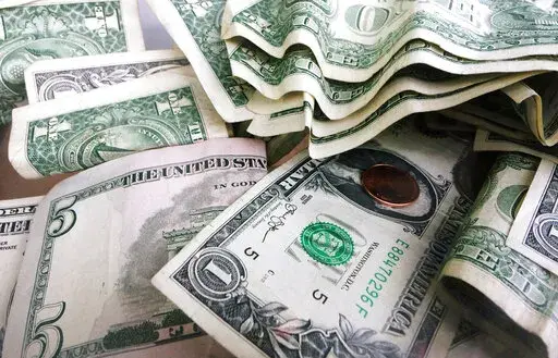 FILE- This Sept. 6, 2017, file photo shows a tip jar with one dollar and five dollar bills and a penny in New York. Millions of Americans deal with food, housing and general financial insecurity every year. Getting help can be tedious and time consuming, especially if you’re facing language barriers, don’t have reliable internet access or simply don’t have the bandwidth because you’re caring and providing for your family. Nonprofit organizations like 211.org and the National Low Income H