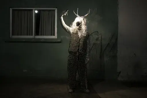 A man poses for a photo wearing a costume during a Muerteada parade in San Agustin Etla, Thursday, Nov. 2, 2023. Mexicans in the Oaxacan town celebrate the traditional Muerteada, a theatrical recreation that is performed through the night of November 1 until the early morning of the following day, with dances and music parading through the streets, while telling the story of how a deceased person is resurrected with the help of a priest, a doctor and a spiritist. (AP Photo/Maria Alferez)