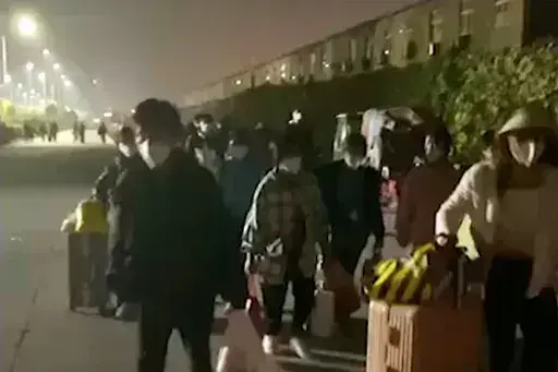 In this photo taken from video footage and released by Hangpai Xingyang, people with suitcases and bags are seen leaving from a Foxconn compound in Zhengzhou in central China's Henan Province on Saturday, Oct. 29, 2022. Workers in a Foxconn facility in the central Chinese city of Zhengzhou appear to have left the facility to avoid COVID-19 curbs, with many traveling by foot days after an unknown number of factory workers were quarantined in the facility following a virus outbreak. (Hangpai Xingy