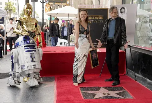Mark Hamill, from right, and Billie Lourd, daughter of the late actress Carrie Fisher, pose with Fisher's star on the Hollywood Walk of Fame alongside "Star Wars" characters C-3PO and R2-D2 during a posthumous ceremony in Los Angeles on Thursday, May 4, 2023. The day is also known as May the Fourth in tribute to the "Star Wars" films in which Fisher played Princess Leia. (AP Photo/Chris Pizzello)