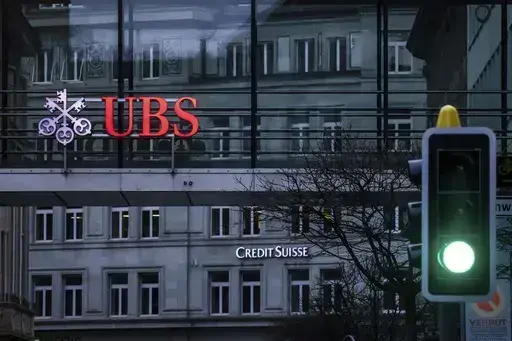A traffic light signals green in front of the logos of the Swiss banks Credit Suisse and UBS in Zurich, Switzerland, on March 19, 2023. Analysts say the UBS takeover of embattled rival Credit Suisse has shaken Switzerland’s self-image and dented its reputation as a global financial center. They warn that the country’s prosperity could grow too dependent on a single banking behemoth. (Michael Buholzer/Keystone via AP, File)