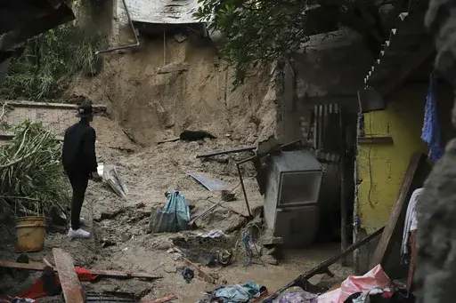A relative stands outside the home where two girls died when their home was buried in a landslide, in San Salvador, El Salvador, Friday, June 21, 2024. The torrential rains hitting El Salvador caused more deaths on Friday. (AP Photo/Salvador Melendez)