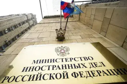 A Russian national flag flutters in the wind next to the sign of the Russian Foreign Ministry building in Moscow, Russia, Wednesday, Jan. 26, 2022. Russian Foreign Minister Sergey Lavrov said he and other top officials will advise President Vladimir Putin on the next steps after receiving written replies from the United States to the demands. Those answers are expected this week — even though the U.S. and its allies have already made clear they will reject the top Russian demands. (AP Photo/Al