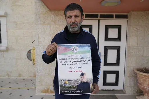 Khalid Ahmad holds a poster of his 17-year-old son, Waleed, who died in an Israeli prison, that reads in Arabic, "The hero prisoner Martyr, mercy and eternity for our righteous Martyrs," in the West Bank town of Silwad, northeast of Ramallah Wednesday, March 26, 2025. (AP Photo/Nasser Nasser)