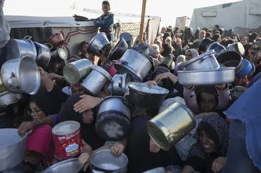 Palestinian women and girls struggle to reach for food at a distribution center in Khan Younis, Gaza Strip Friday, Dec. 6, 2024. (AP Photo/Abdel Kareem Hana, File)