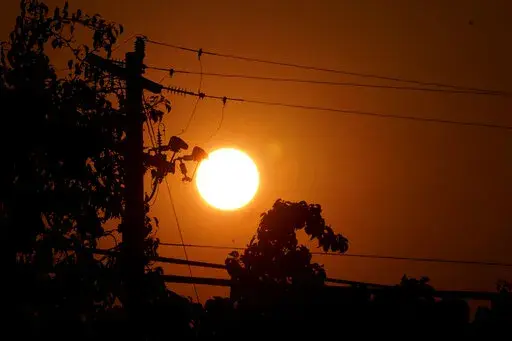Sunrise is viewed between power lines in Sacramento, Calif., Thursday, Sept. 8, 2022. The record-breaking heat that has pushed the state's electrical grid to the brink of power outages for more than a week is almost over but it is a sign of things to come. (AP Photo/Rich Pedroncelli, File)