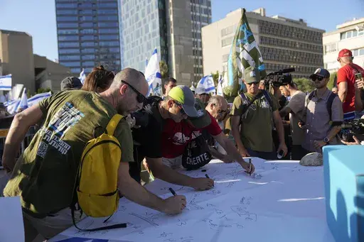Israeli military reservists sign a declaration of refusal to report for duty to protest against plans by Prime Minister Benjamin Netanyahu's government to overhaul the judicial system, in Tel Aviv, Israel, Wednesday, July 19, 2023. Divisions over the contentious government plan have infiltrated the country's military, where reservists in key units have pledged not to show up for duty if the legislative changes are approved. (AP Photo/Ohad Zwigenberg)