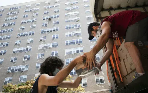 Jakob Howell, left, and Matt Brown load boxes belonging to Joyce and Anil Lilly into a moving truck, Tuesday, July 21, 2020, in The Bronx borough of New York. The number of former Californians who became new Texans dropped slightly last year, and some of that slack was picked up by Florida which saw its share of ex-Californians grow, according to new state-to-state migration figures released Thursday, Oct. 19, 2023. (AP Photo/Mark Lennihan, File)