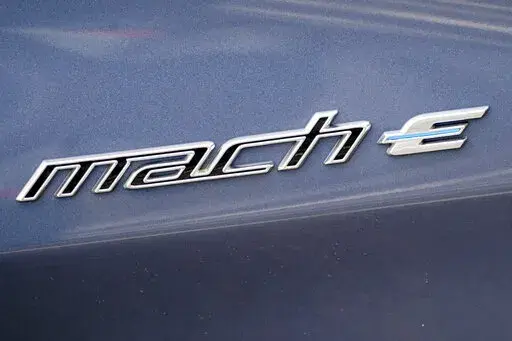 In this photo made on Thursday, May 6, 2021, the badging logo is seen on a 2021 Ford Mustang Mach E at a Ford dealer in Wexford, Pa. Ford is spinning off its electric vehicles and internal combustion businesses into separate units. The automaker said Wednesday, March 2, 2022 that its plan includes two distinct, but strategically interdependent, auto businesses – Ford Blue and Ford Model e.  (AP Photo/Keith Srakocic)