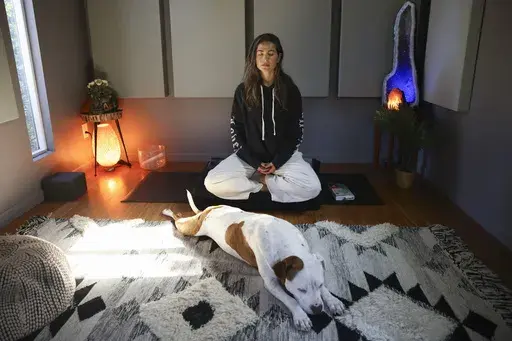 Headspace meditation teacher, Rosie Acosta, meditates in her studio with her dog Monday, Sept. 30, 2024, in Woodland Hills, Calif. (AP Photo/Jessie Alcheh)