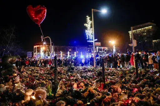 People attend an AfD election campaign in near the Christmas Market in Magdeburg, Germany, Monday, Dec. 23, 2024. (AP Photo/Ebrahim Noroozi)