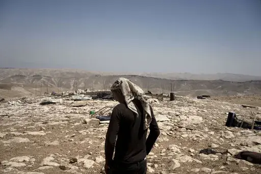 Palestinian shepherd Mustafa Arara, 24, stands in the ruins of the West Bank Bedouin village of al-Baqa where residents fled in July after settlers established an outpost a stone's throw from the village in June, Wednesday, Aug. 9, 2023. Out of 33 people who fled the Palestinian hamlet east of Ramallah, just one six-person family has returned after settlers from a newly established outpost wreaked havoc on the village, setting their sheep loose on Palestinian grazing fields and torching a home. 