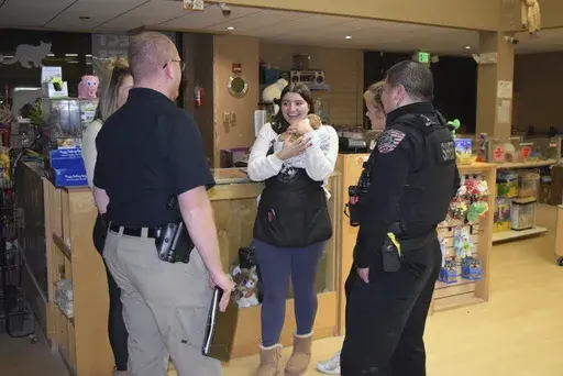 In this photo released by the Arapahoe County Sheriff’s Office, a Perfect Pets worker holds one of two bulldog puppies stolen from the store, after the dogs were returned by a person who bought the dogs from a street vendor, in Centennial, Colorado, Monday, Feb. 24, 2025. (Arapahoe County Sheriff’s Office via AP)