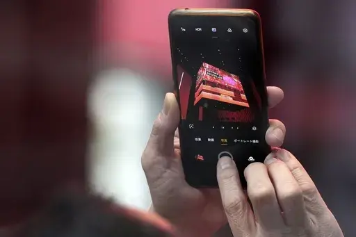 A person takes photograph an electronic stock board showing Japan's Nikkei 225 index at a securities firm Thursday, Feb. 22, 2024, in Tokyo. Japan’s benchmark Nikkei 225 index surged Thursday past the record it set in 1989 before its financial bubble burst, ushering in an era of faltering growth. (AP Photo/Eugene Hoshiko)
