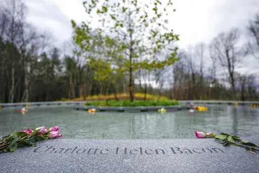 Flowers lay next to the name of Charlotte Bacon, carved in the stone of a memorial dedicated to the victims of the Sandy Hook Elementary School shooting, in Newtown, Conn., Sunday, Nov. 13, 2022. (AP Photo/Bryan Woolston)
