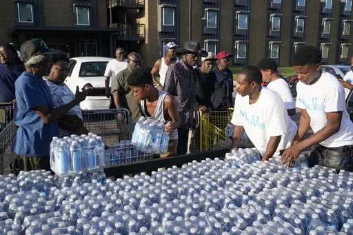 Residents of the Golden Keys Senior Living apartments flock to a trailer full of water being delivered by the AIDS Healthcare Foundation in Jackson, Miss., on Sept. 1, 2022. Southern Poverty Law Center announced Friday, May 5, 2023, that it had filed a federal civil rights complaint saying the state of Mississippi had created hurdles that prevent the majority-Black capital city of Jackson from receiving enough money to repair a long-troubled water system. (AP Photo/Steve Helber, File)
