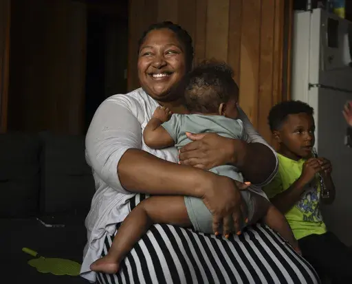 Alexis Ratliff, 29, sits with her 11-month-old daughter, Eleah Witcher, and son, Ezekiel, 5, at home in Rocky Mount, N.C., on July 9, 2024. With no hospital in Rocky Mount, Ratliff had a doula to help with the birth of Eleah. (Natalee Waters/Cardinal News, CatchLight Local via AP)