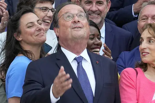 Former French President Francois Hollande looks up as he poses with newly elected parliament members of the Socialist party, at the National Assembly, Tuesday, July 9, 2024 in Paris. French voters have given a broad leftist coalition the most parliamentary seats in a pivotal legislative election that has kept the far right from power but has put France in the unprecedented position of having no dominant political bloc in parliament. (AP Photo/Michel Euler)