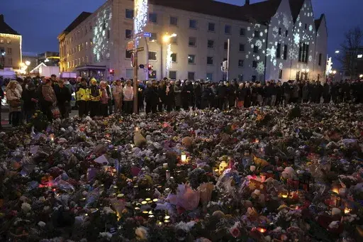 Flowers, candles and wide offerings of mourning in front of St. John's Church, close to the Christmas market where a car drove into a crowd on Friday evening, in Magdeburg, Germany, Monday, Dec. 23, 2024. (Sebastian Willnow/dpa via AP)