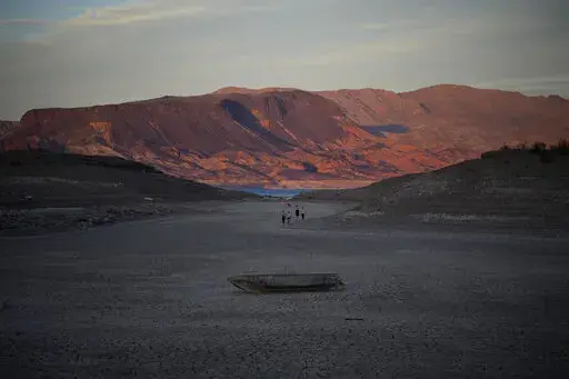 A formally sunken boat sits on cracked earth hundreds of feet from what is now the shoreline on Lake Mead at the Lake Mead National Recreation Area, Monday, May 9, 2022, near Boulder City, Nev. Lake Mead is receding and Sin City is awash with mob lore after a second set of human remains emerged within a week from the depths of the drought-stricken Colorado River reservoir just a short drive from the Las Vegas Strip.  (AP Photo/John Locher)