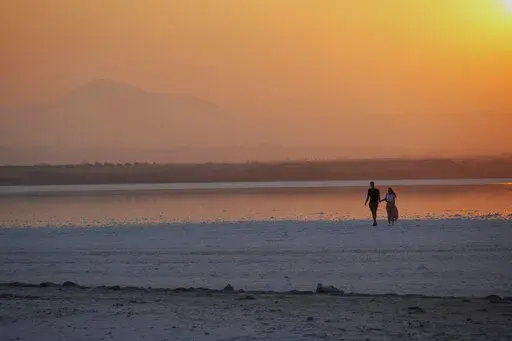 A couple walk at the salt lake during sunset in southeast coastal city of Larnaca in southeast Mediterranean island of Cyprus, on Sept. 5, 2022. The eastern Mediterranean and Middle East are warming almost twice as fast as the global average, with temperatures projected to rise up to 5 degrees Celsius (9 degrees Fahrenheit) by the end of the century if no action is taken to reverse the trend, a new report says. (AP Photo/Petros Karadjias, File)