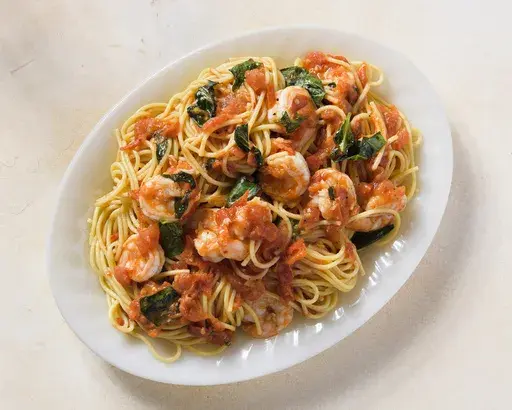 This image released by Milk Street shows a recipe for spaghetti with shrimp, tomatoes and white wine. (Milk Street via AP)
