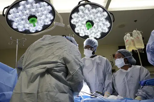 Meharry Medical College students Emmanuel Kotey, center, and Teresa Belledent, right, watch as the liver and kidneys are removed from an organ donor June 15, 2023, in Jackson, Tenn. They’re part of a novel pilot program to encourage more Black and other minority doctors-to-be to get involved in the transplant field, increasing the trust of patients of color. (AP Photo/Mark Humphrey)