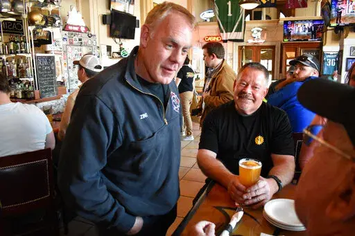 Montana U.S. House candidate and former Secretary of Interior Ryan Zinke, left, speaks with patrons at Metals Sports Bar and Grill, May 13, 2022, in Butte, Mont. Zinke is seeking election to a newly created U.S. House district. (AP Photo/Matthew Brown, File)