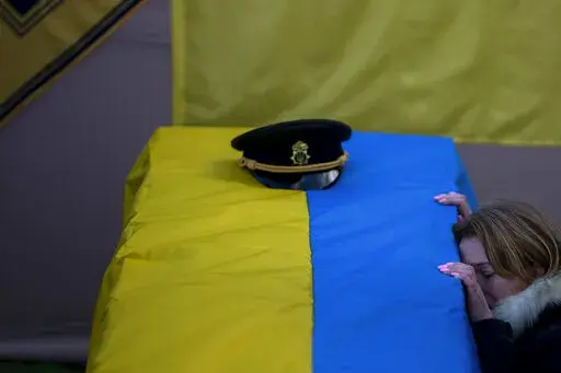 Svitlana kneels next to the coffin of her husband Serhii, 48, during his funeral in Tarasivka village, near Kyiv, Ukraine, Wednesday, Feb. 15, 2023. Serhii Havryliuk, an officer of the Azov Assault Brigade, died while defending the Azovstal steel plant in Mariupol on April 12, 2022 against the Russians. Serhii has finally been buried after DNA tests confirmed his identity. (AP Photo/Emilio Morenatti)