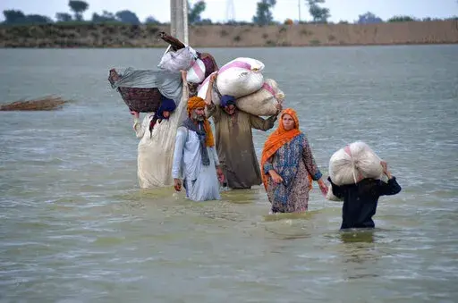 A displaced family wades through a flooded area after heavy rainfall, in Jaffarabad, a district of Pakistan's southwestern Baluchistan province, Aug. 24, 2022. A new study says human-caused climate change juiced the rainfall that triggered Pakistan's floods by up to 50%. But the authors of the Thursday, Sept. 15, study say other societal issues that make the country vulnerable and put people in harm's way are probably the biggest factor in the ongoing humanitarian disaster. (AP Photo/Zahid Hussa