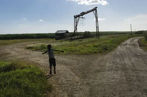 A youth plays near the machine where the sugar cane is weighed in the Lima batey, or neighborhood, in La Romana, where Central Romana Corporation, Ltd. operates its sugar operations in Dominican Republic, Nov. 17, 2021. The U.S. government announced Nov. 23, 2022 that it will detain all imports of sugar and related products made in the Dominican Republic by Central Romana Corporation, Ltd. amid allegations that it uses forced labor. (AP Photo/Matias Delacroix, File)