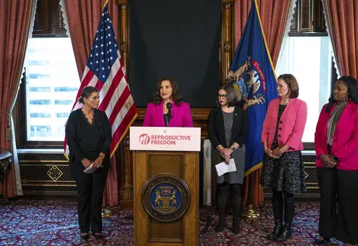 Michigan Gov. Gretchen Whitmer talks with the press before signing the final bill in the Reproductive Health Act on Monday, Dec. 11, 2023, at the Michigan State Capitol building in Lansing, Mich. The bill repeals Michigan's ban on insurance coverage for abortion without the purchase of a separate rider and implements other protections for doctors and patients. (Ryan Garza/Detroit Free Press via AP)