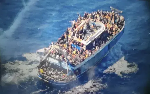 In this undated photo provided by Greece's coast guard on Wednesday, June 14, 2023, scores of people sit on a battered fishing boat that later capsized and sank off southern Greece. The sinking of the Adriana a year ago in international waters 75 kilometers (45 miles) off southern Greece was one of the worst of its kind in the Mediterranean Sea. Only 82 bodies were recovered, so hundreds of families still lack even the grim satisfaction of certitude that their relatives are dead. (Hellenic Coast